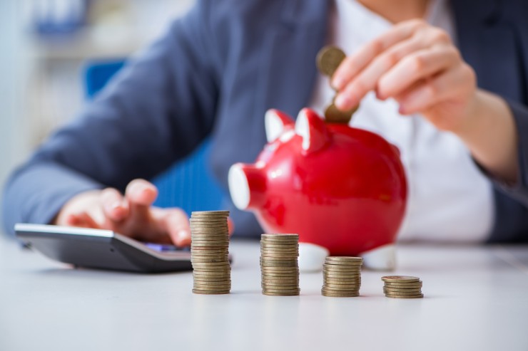 pensionata con calcolatrice monete e salvadanaio